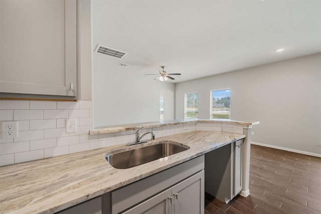 kitchen with light stone counters, sink, and gray cabinets