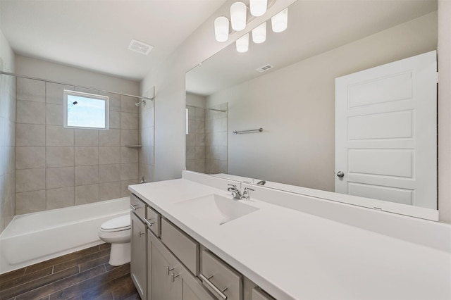 full bathroom with tiled shower / bath, vanity, and toilet