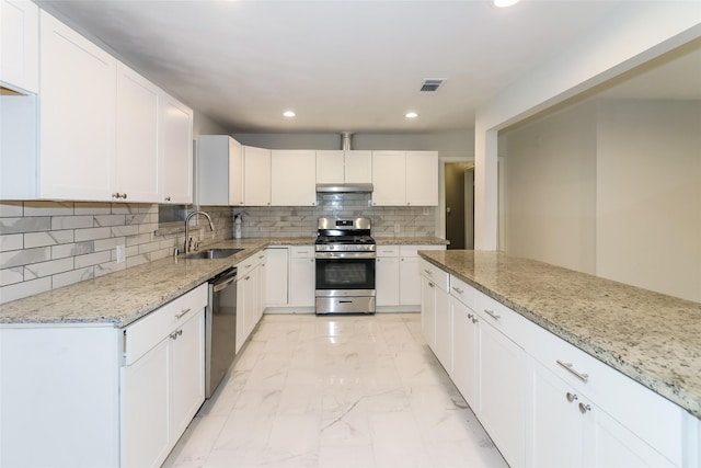 kitchen with white cabinetry, appliances with stainless steel finishes, sink, and light stone counters