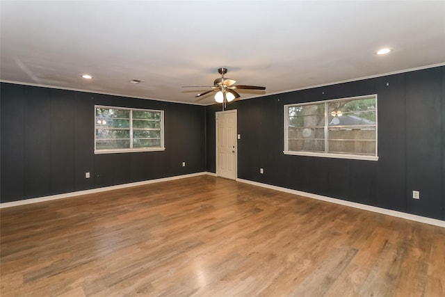 spare room featuring wood-type flooring, crown molding, a wealth of natural light, and ceiling fan