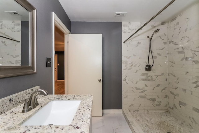 bathroom with vanity and a tile shower