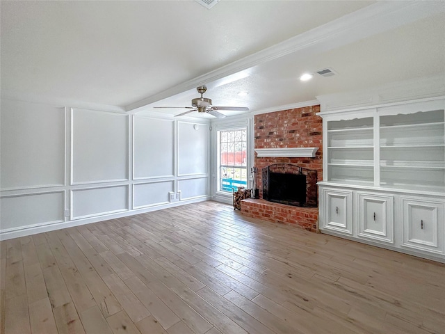 unfurnished living room featuring ceiling fan, a brick fireplace, crown molding, and light hardwood / wood-style floors