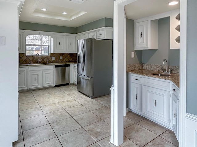 kitchen with white cabinetry, sink, light stone counters, and appliances with stainless steel finishes