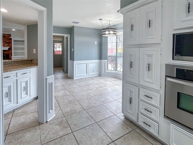 kitchen featuring decorative light fixtures, white cabinets, light tile patterned floors, light stone counters, and stainless steel appliances