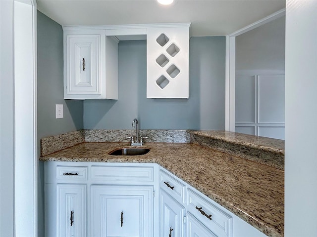 kitchen with light stone counters, sink, and white cabinets