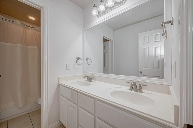 bathroom with tile patterned floors, toilet, and double vanity