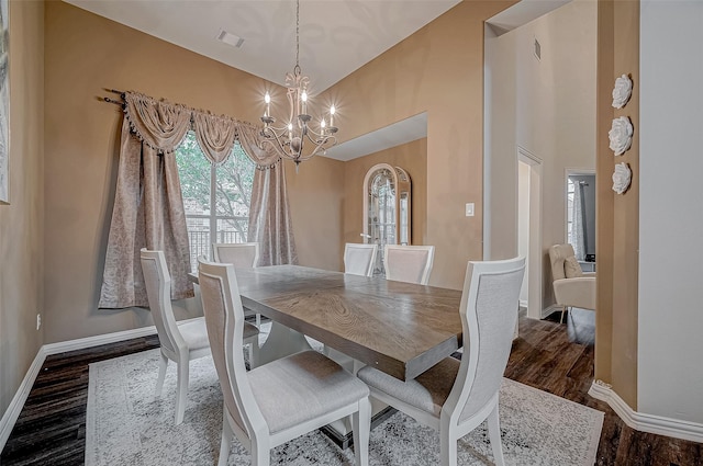dining area with a chandelier, baseboards, wood finished floors, and high vaulted ceiling