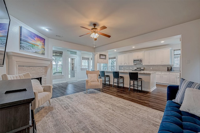 living area featuring a ceiling fan, dark wood finished floors, recessed lighting, and a fireplace