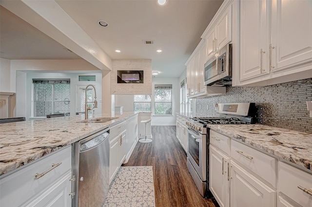kitchen featuring stainless steel appliances, dark wood finished floors, a sink, white cabinetry, and recessed lighting
