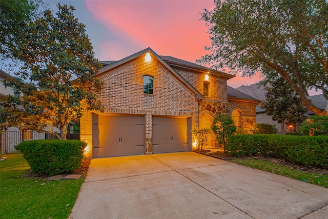 view of front facade with brick siding, concrete driveway, an attached garage, and fence