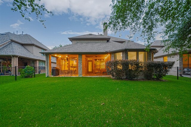 back of property with brick siding, ceiling fan, a chimney, and roof with shingles