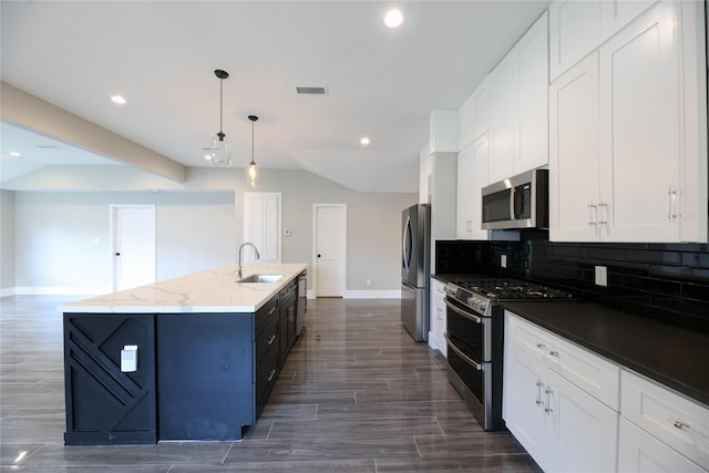 kitchen featuring sink, white cabinets, hanging light fixtures, stainless steel appliances, and a center island with sink