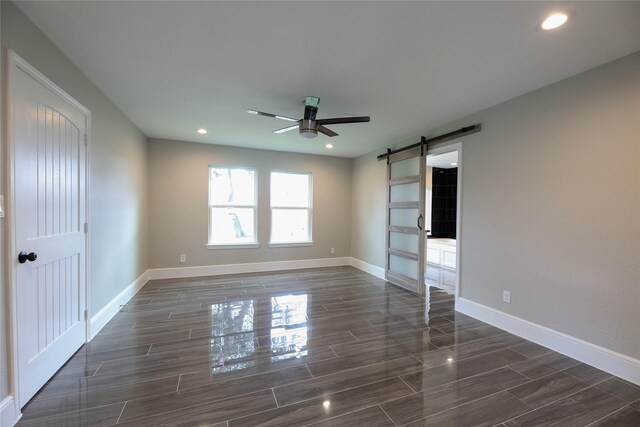 spare room with a barn door and ceiling fan