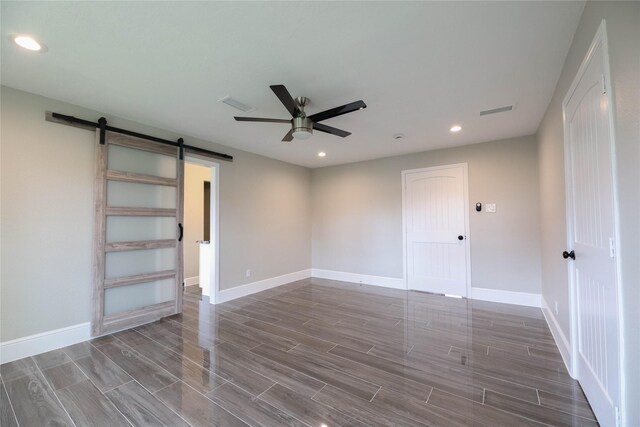 empty room with a barn door and ceiling fan