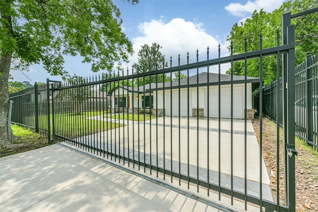 view of gate with a garage and a lawn