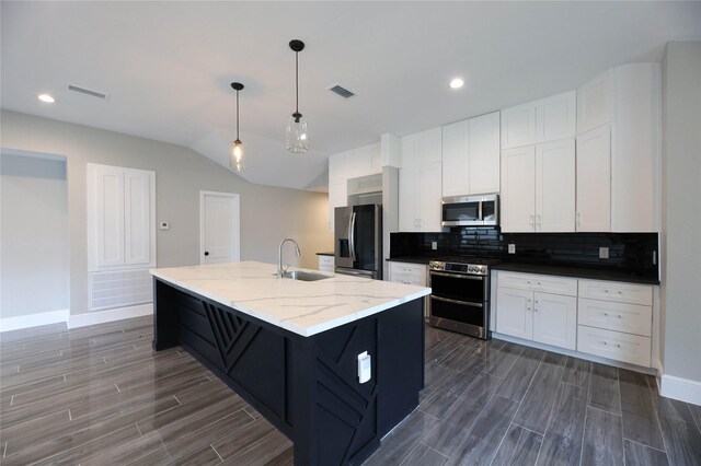 kitchen with sink, light stone counters, an island with sink, stainless steel appliances, and white cabinets