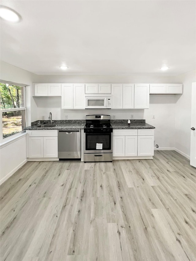 kitchen featuring appliances with stainless steel finishes, sink, light hardwood / wood-style flooring, and white cabinets