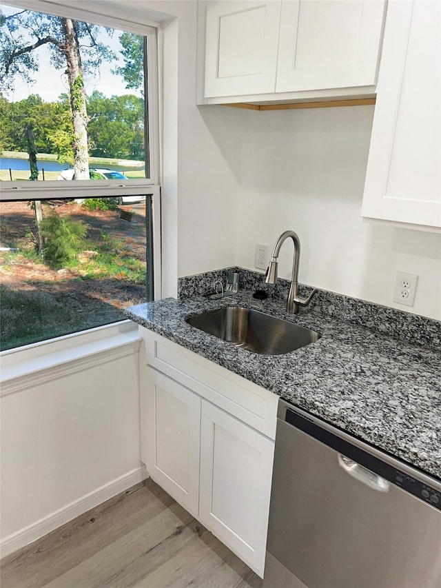 kitchen featuring dark stone counters, dishwasher, sink, and white cabinets