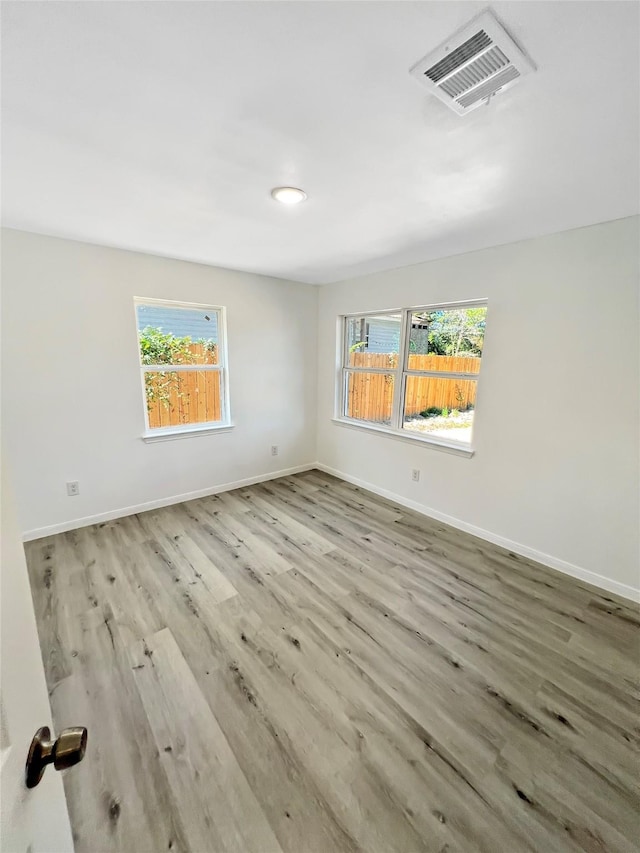 empty room with a healthy amount of sunlight and light hardwood / wood-style flooring