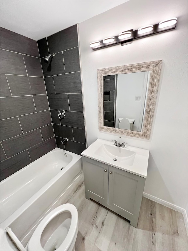 full bathroom featuring tiled shower / bath combo, vanity, hardwood / wood-style floors, and toilet