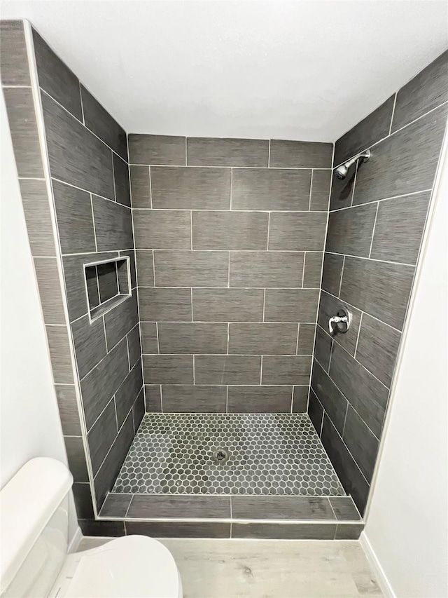 bathroom with a tile shower and toilet