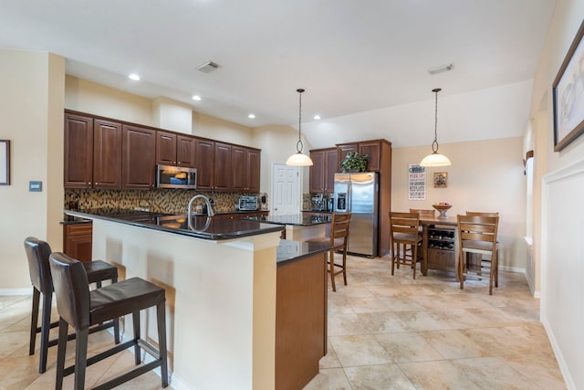 12622 Baldwin Springs Ct, Tomball, TX 77377 - kitchen with stainless steel appliances, a breakfast bar area, dark countertops, decorative backsplash, and lofted ceiling