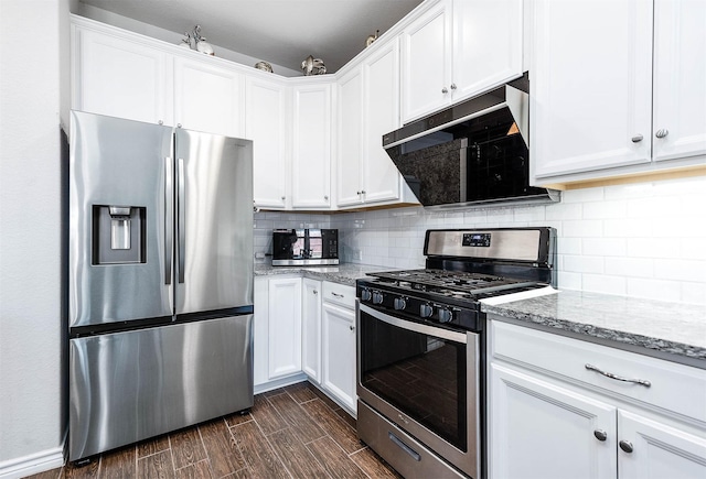 kitchen featuring stainless steel appliances, white cabinetry, light stone countertops, and decorative backsplash