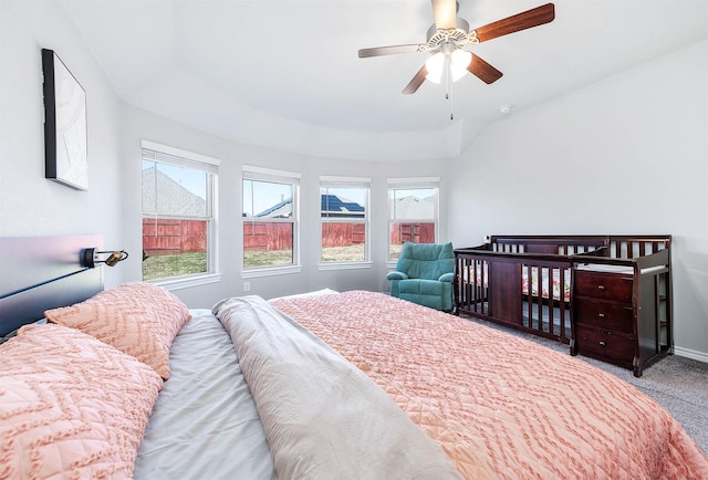 carpeted bedroom with ceiling fan and a raised ceiling