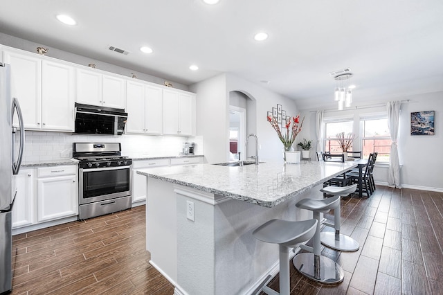 kitchen with stainless steel appliances, a kitchen island with sink, sink, and white cabinets