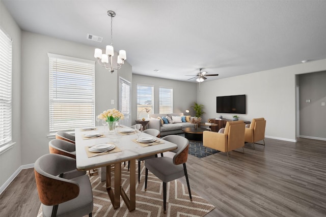 dining room with dark hardwood / wood-style floors and ceiling fan with notable chandelier