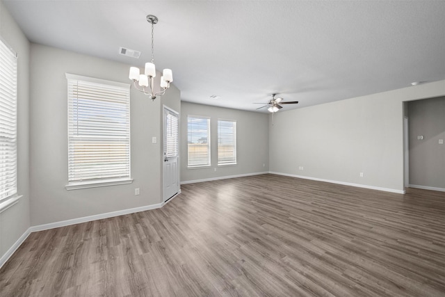 spare room with ceiling fan with notable chandelier and dark wood-type flooring