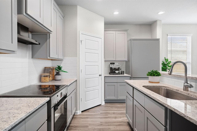 kitchen featuring gray cabinets, appliances with stainless steel finishes, sink, light stone counters, and light wood-type flooring