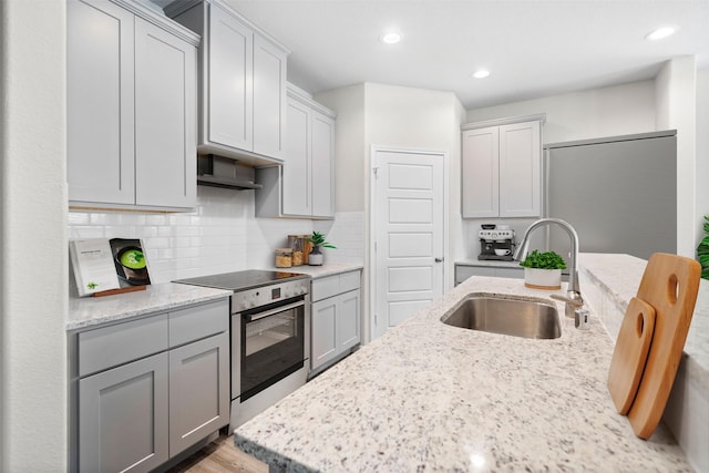 kitchen with stainless steel electric stove, tasteful backsplash, sink, gray cabinetry, and light stone counters