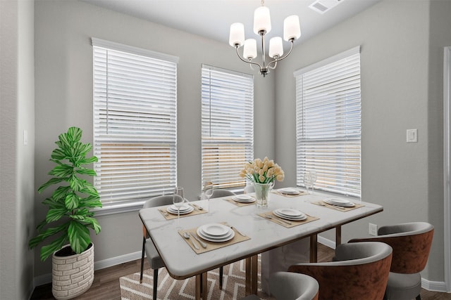 dining space with dark wood-type flooring and a chandelier