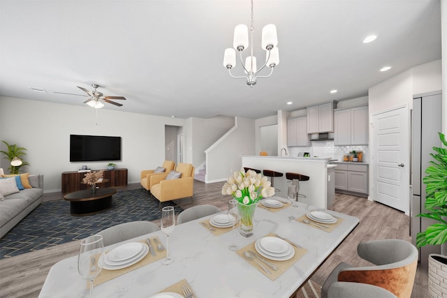 dining area featuring ceiling fan with notable chandelier and light hardwood / wood-style flooring