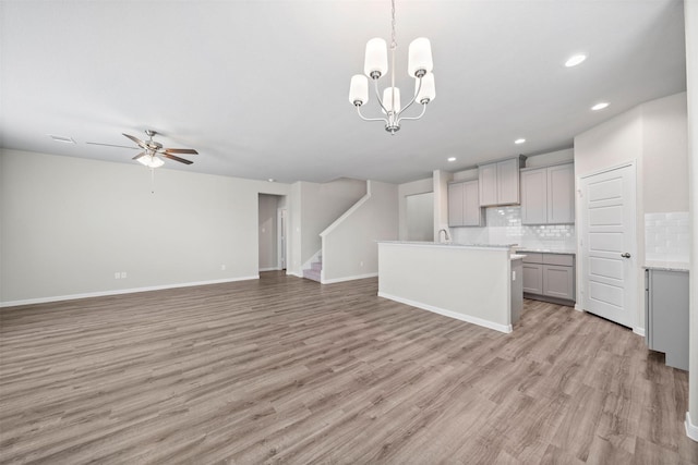 kitchen with decorative backsplash, decorative light fixtures, light hardwood / wood-style flooring, and gray cabinetry