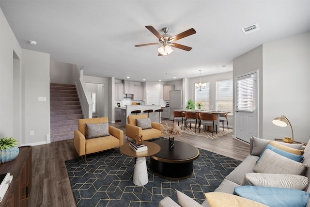 living room featuring dark wood-type flooring and ceiling fan with notable chandelier