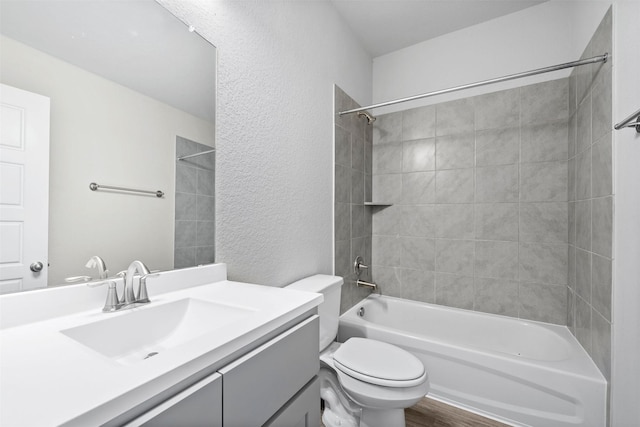 full bathroom featuring tiled shower / bath, hardwood / wood-style floors, vanity, and toilet