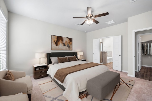 bedroom with ceiling fan, ensuite bath, light carpet, and multiple windows