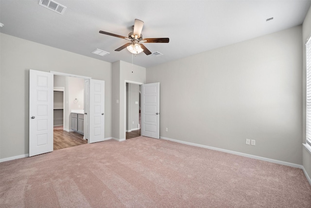 unfurnished bedroom with ceiling fan, ensuite bath, and light carpet