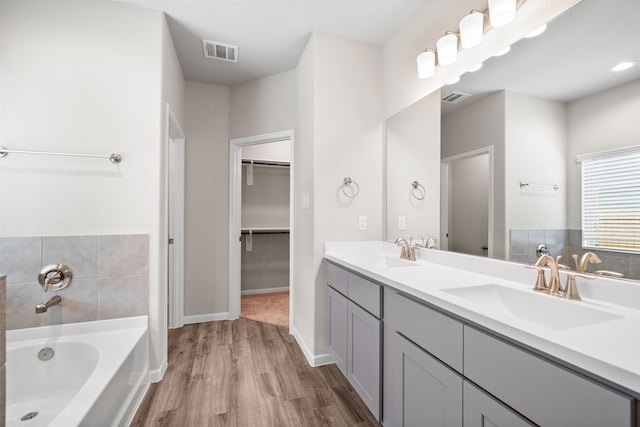 bathroom with vanity, a bathing tub, and wood-type flooring