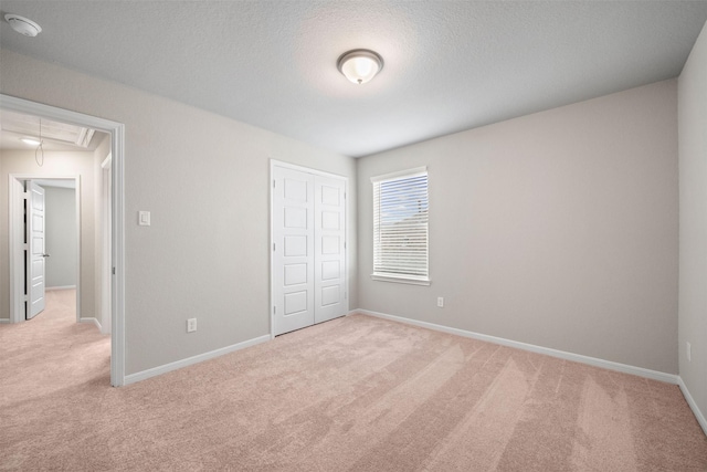 unfurnished bedroom featuring light carpet, a textured ceiling, and a closet