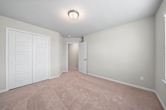 unfurnished bedroom featuring a closet and light carpet