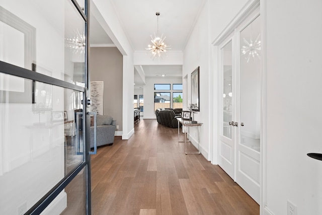 hall featuring ornamental molding, hardwood / wood-style floors, a chandelier, and french doors