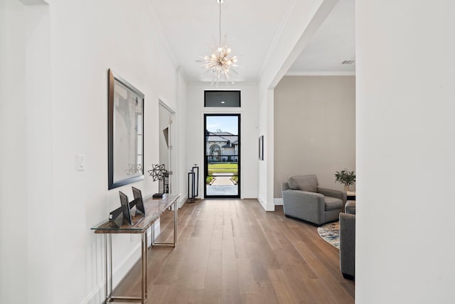 foyer entrance featuring crown molding, wood-type flooring, and a chandelier