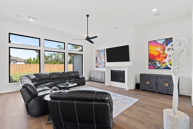 living room with wood-type flooring, crown molding, and ceiling fan