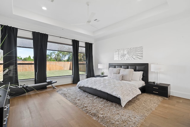 bedroom with light hardwood / wood-style floors and a tray ceiling