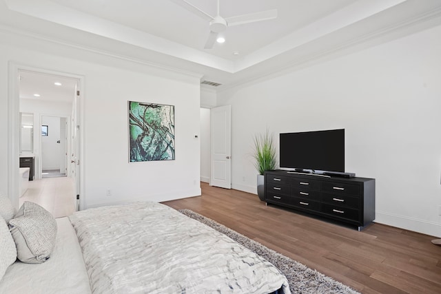 bedroom featuring ceiling fan, wood-type flooring, and a raised ceiling