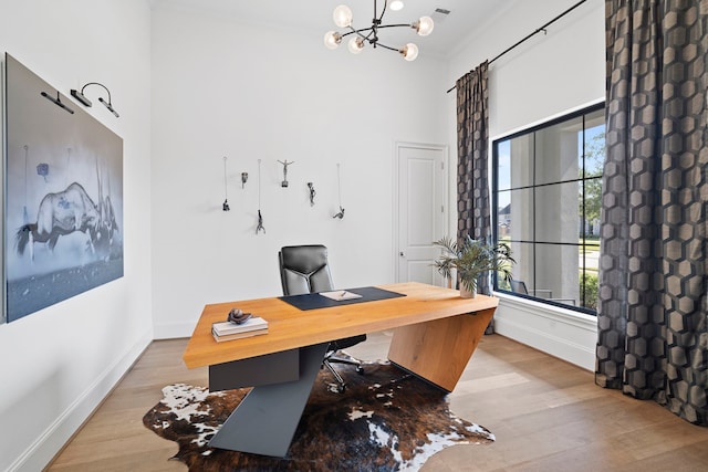 office area with a high ceiling, crown molding, a chandelier, and light wood-type flooring