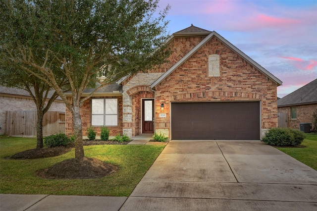 front of property featuring a garage, a yard, and central AC unit